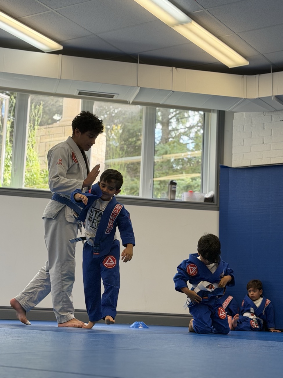 A coach welcoming and guiding a student on the mats